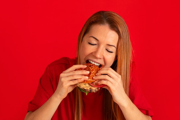 Foto gratuita vista frontal mujer joven comiendo hamburguesa