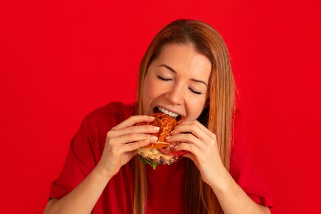 Vista frontal mujer joven comiendo hamburguesa