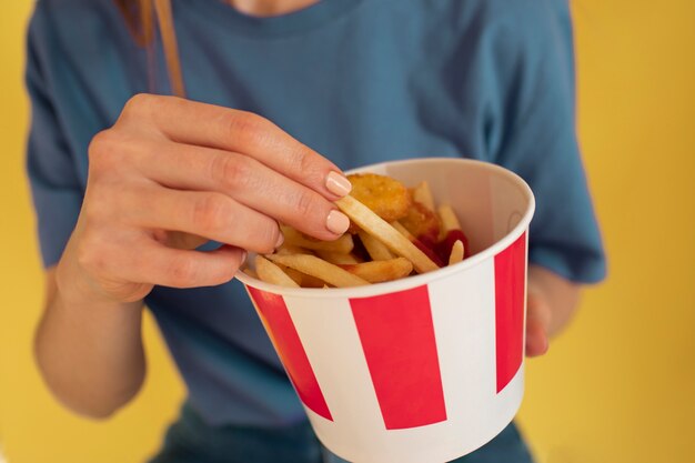 Vista frontal mujer joven comiendo papas fritas