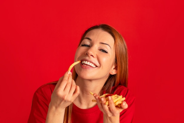 Vista frontal mujer joven comiendo papas fritas