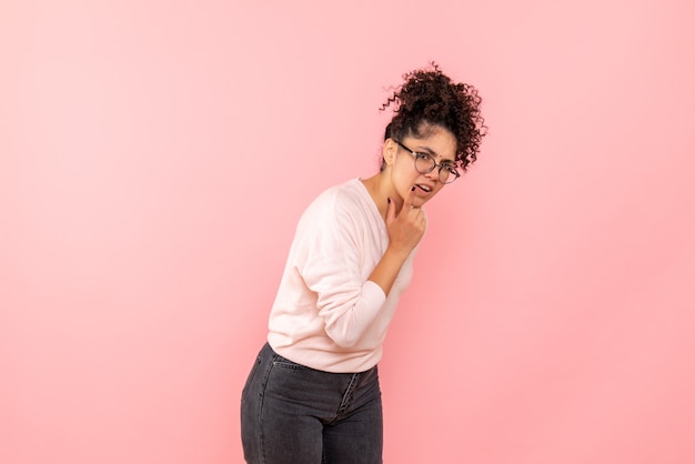 Vista frontal de la mujer joven confundida en la pared rosa