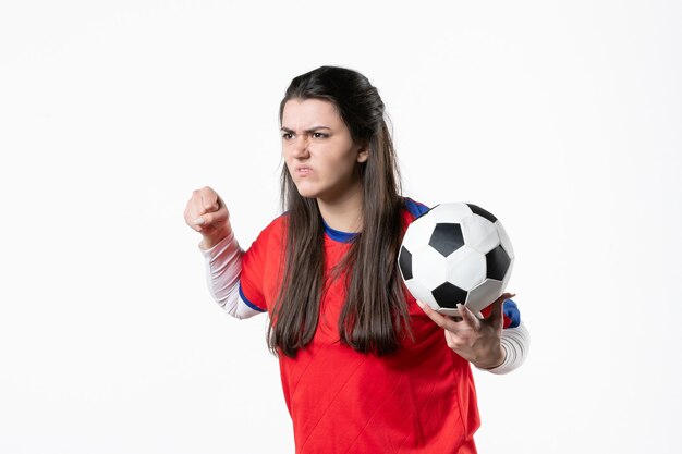 Vista frontal mujer joven enojada en ropa deportiva con balón de fútbol