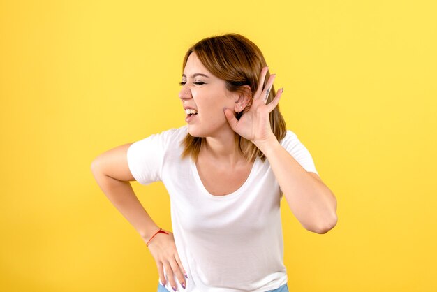 Vista frontal, de, mujer joven, escuchar, en, pared amarilla