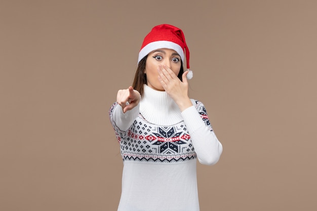 Vista frontal mujer joven con expresión de asombro sobre fondo marrón año nuevo emoción navidad