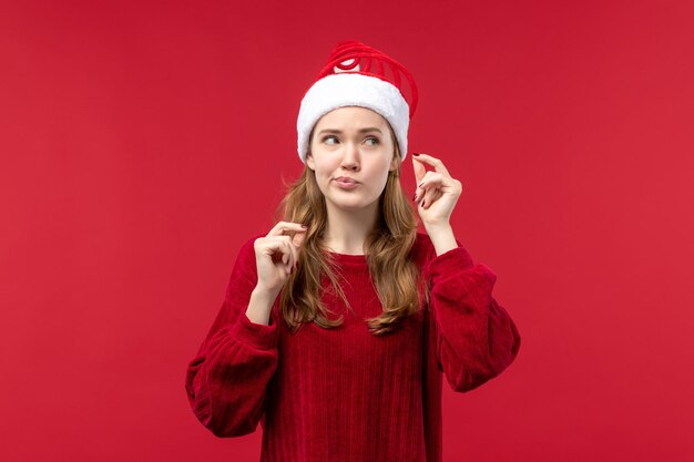 Vista frontal de la mujer joven con expresión confusa en el escritorio rojo Navidad vacaciones rojo