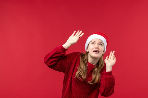 Vista frontal mujer joven con expresión emocionada en rojo escritorio rojo de vacaciones de Navidad