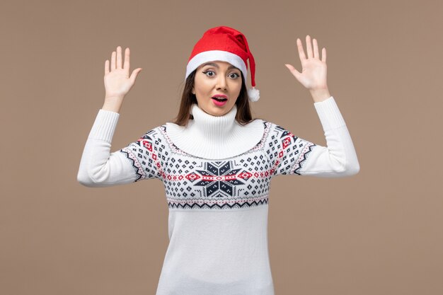 Vista frontal mujer joven con expresión emocionada sobre fondo marrón Navidad emoción año nuevo