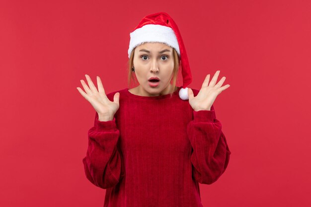 Vista frontal mujer joven con expresión nerviosa, rojo vacaciones navidad