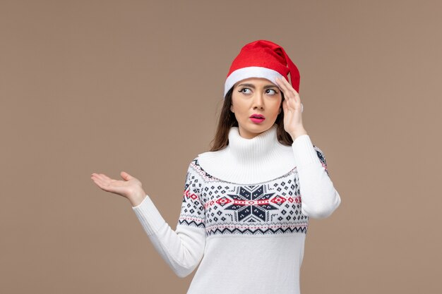 Vista frontal mujer joven con expresión de pensamiento sobre fondo marrón vacaciones emoción navidad