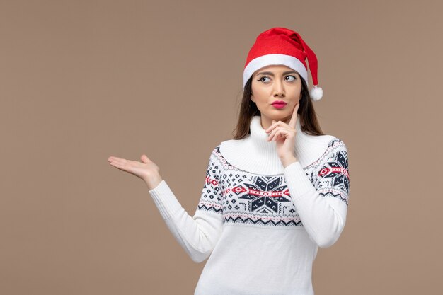 Vista frontal mujer joven con expresión de pensamiento sobre fondo marrón vacaciones emoción navidad