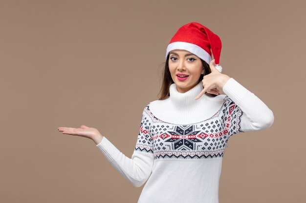 Vista frontal mujer joven con expresión sonriente sobre fondo marrón vacaciones emoción navidad