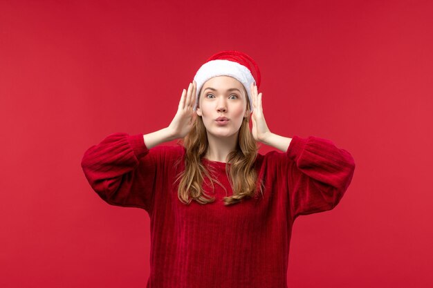 Vista frontal mujer joven con expresión de sorpresa, vacaciones de Navidad roja
