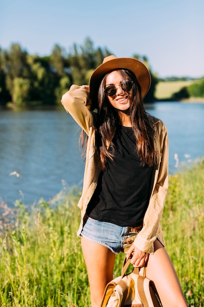 Vista frontal de una mujer joven feliz posando cerca de río