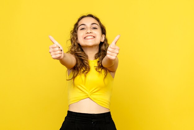 Vista frontal, de, mujer joven, felizmente, sonriente, en, pared amarilla