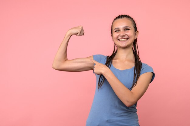 Vista frontal de la mujer joven flexionando con sonrisa en rosa