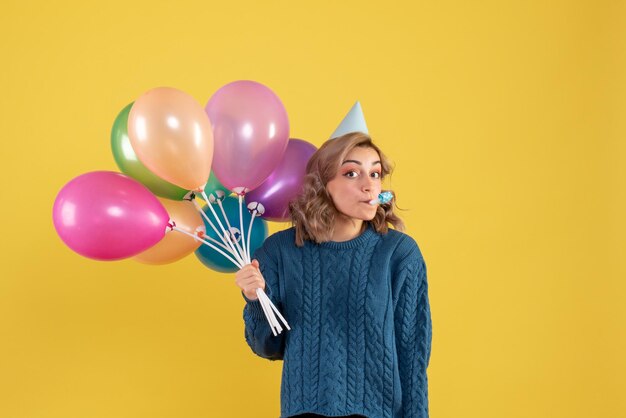 Vista frontal mujer joven con globos de colores