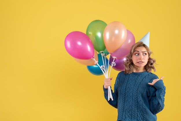 Vista frontal mujer joven con globos de colores