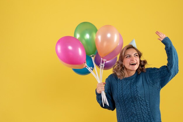 Vista frontal mujer joven con globos de colores