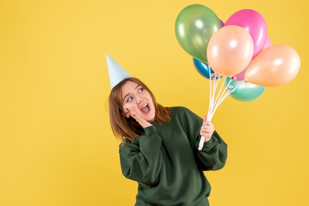 Vista frontal mujer joven con globos de colores