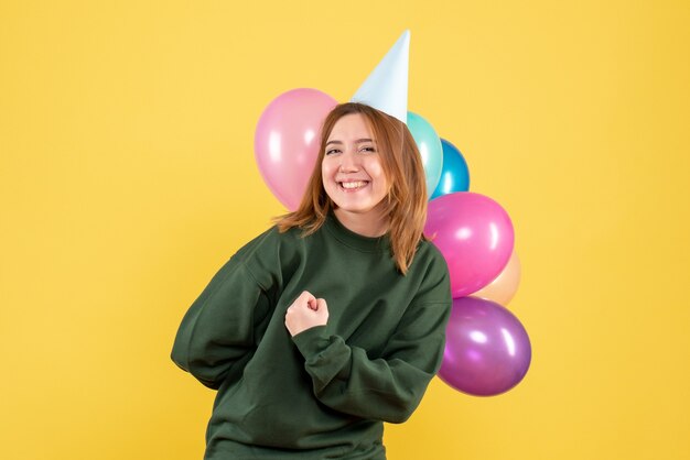 Vista frontal mujer joven con globos de colores