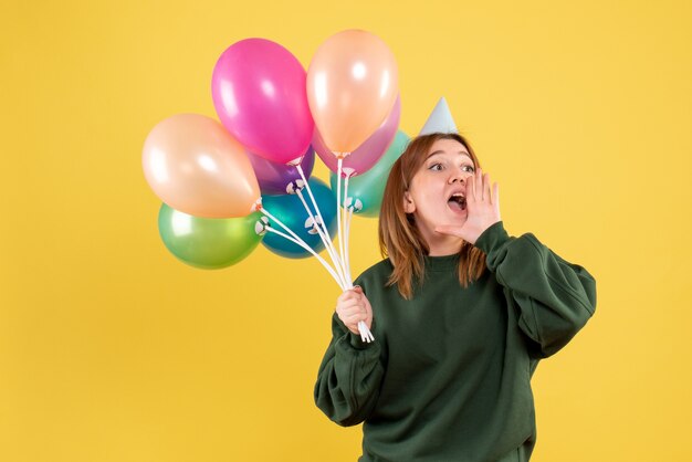 Vista frontal mujer joven con globos de colores