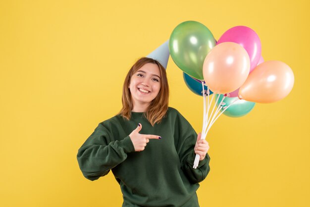 Vista frontal mujer joven con globos de colores