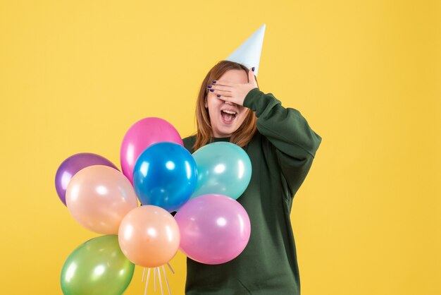 Vista frontal mujer joven con globos de colores