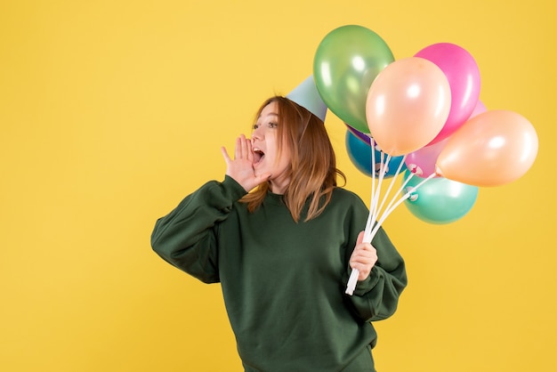 Vista frontal mujer joven con globos de colores