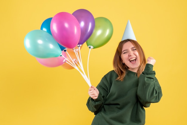 Vista frontal mujer joven con globos de colores