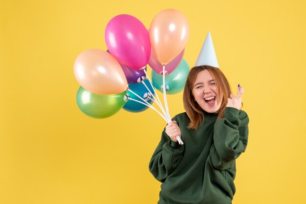 Vista frontal mujer joven con globos de colores