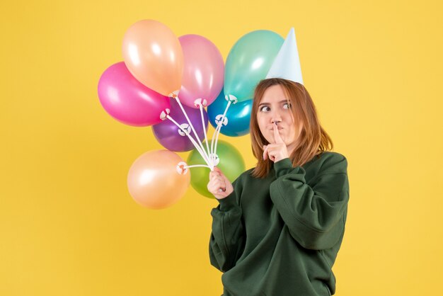 Vista frontal mujer joven con globos de colores