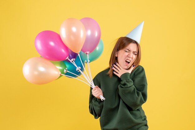 Vista frontal mujer joven con globos de colores