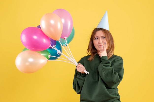 Vista frontal mujer joven con globos de colores