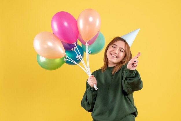 Vista frontal mujer joven con globos de colores