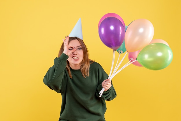 Vista frontal mujer joven con globos de colores