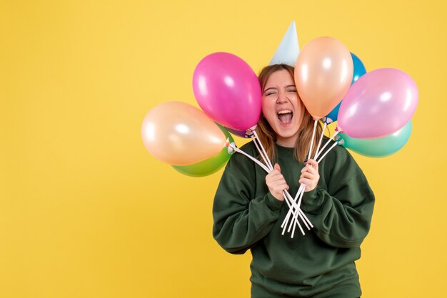 Vista frontal mujer joven con globos de colores