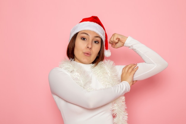 Vista frontal de la mujer joven con gorra roja con guirnaldas en la pared rosa