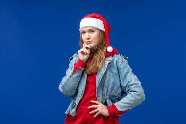 Vista frontal mujer joven con gorra roja pensando en espacio azul