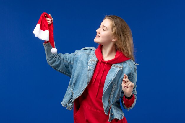 Vista frontal mujer joven con gorra roja sobre escritorio azul vacaciones navidad año nuevo