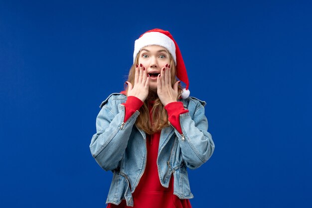 Vista frontal mujer joven con gorra roja sobre fondo azul vacaciones de año nuevo navidad