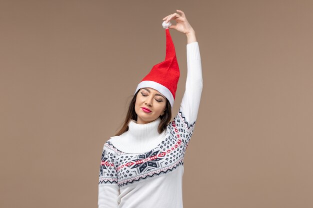 Vista frontal mujer joven con gorro de navidad en el fondo marrón emoción de navidad de vacaciones