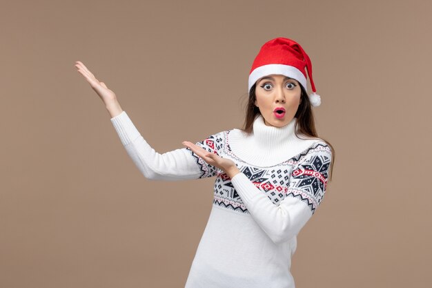 Vista frontal mujer joven con gorro rojo de Navidad en escritorio marrón Navidad emoción año nuevo