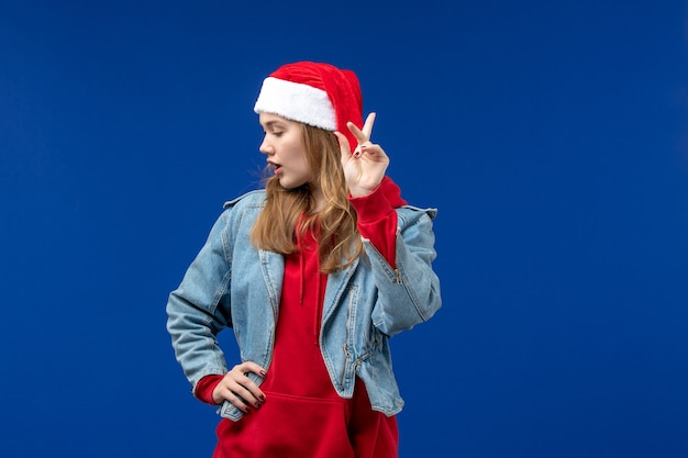 Vista frontal mujer joven con gorro rojo de Navidad en un espacio azul