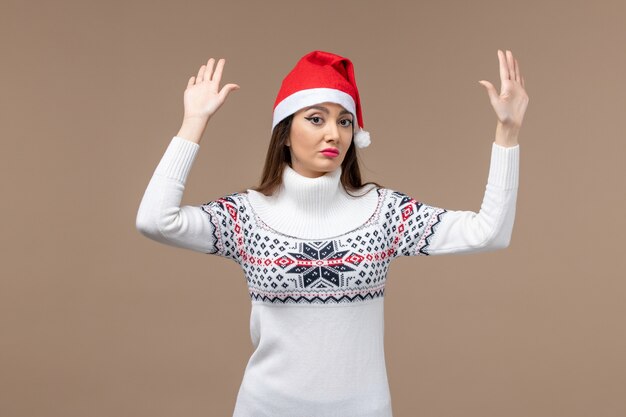 Vista frontal mujer joven con gorro rojo de Navidad sobre fondo marrón emoción de vacaciones de Navidad