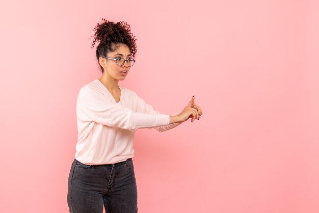 Vista frontal de la mujer joven hablando con alguien en la pared rosa