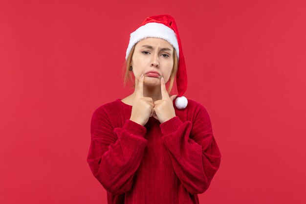 Vista frontal mujer joven haciendo cara triste, rojo vacaciones navidad