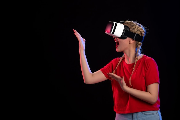 Vista frontal de la mujer joven jugando vr en la pared oscura