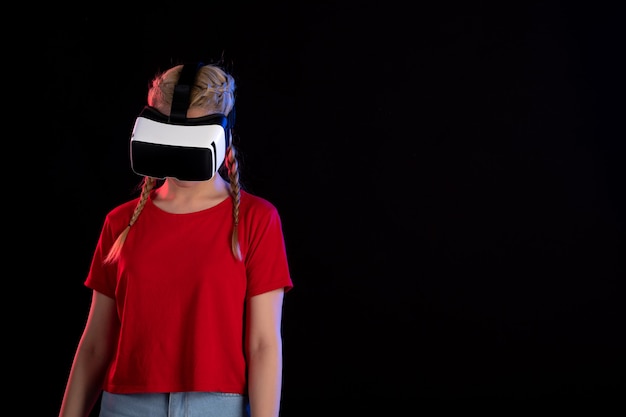 Vista frontal de la mujer joven jugando vr en la pared oscura