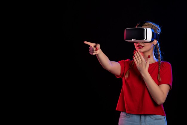 Vista frontal de la mujer joven jugando vr en la pared oscura