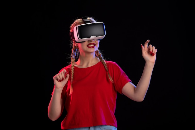 Vista frontal de la mujer joven jugando vr en la pared oscura